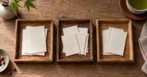 机の上に小さな木のトレーを3つ並べ、無地の紙片を種類ごとに仕分けた俯瞰（イメージ）